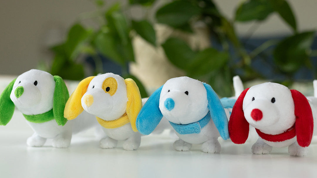 4 colorful plush dachshund dogs lined up on a white table