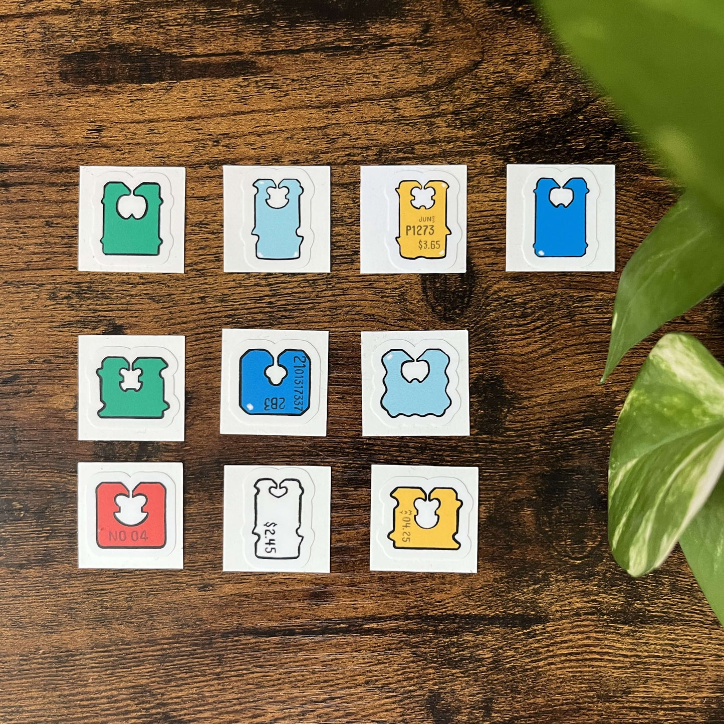 Set of colorful, die-cut, bread clip stickers on a wood background with green leaves coming from the side