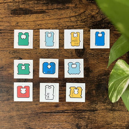 Set of colorful, die-cut, bread clip stickers on a wood background with green leaves coming from the side