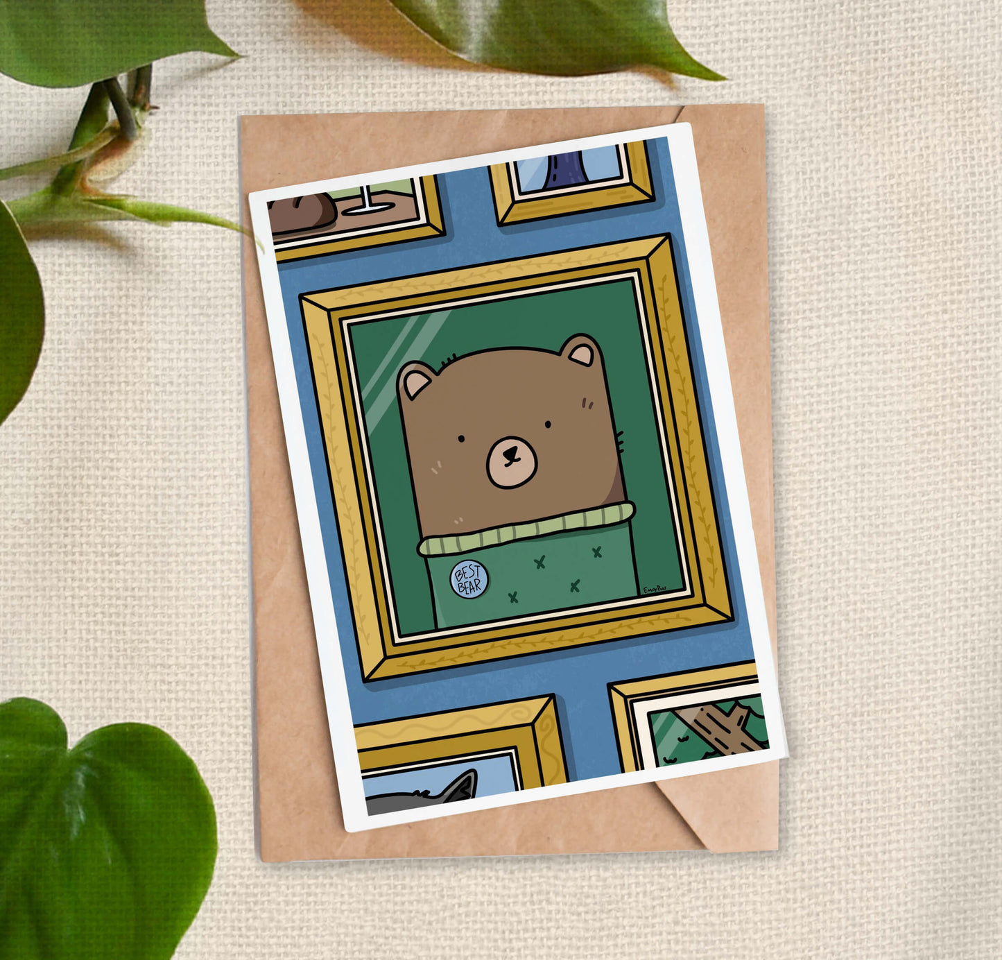 Greeting card with image of framed cartoon of a brown bear wearing a green sweater labeled "Best Bear" on a blue wall.