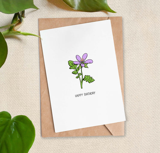 Greeting card illustration of small purple flower with two long green leaves and light text that reads "HAPPY BIRTHDAY".