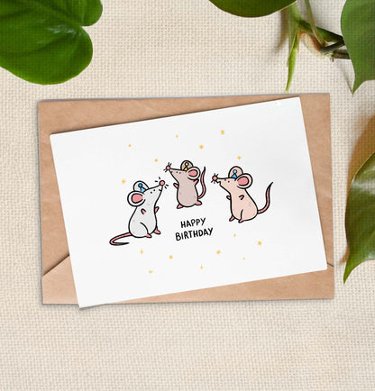 Cartoon on a greeting card of 3 brown and grey rats wearing party hats. They are surrounded by stars with the text "Happy Birthday".