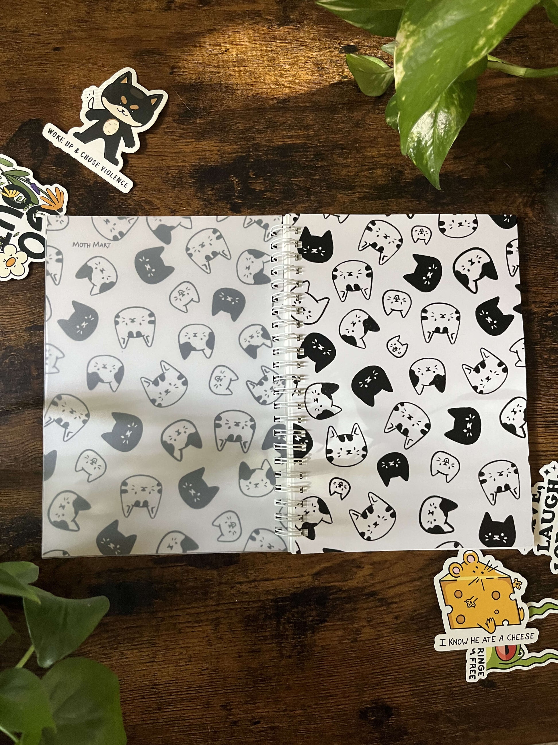 A5 Reusable Cat Sticker book laying flat, depicting black and white cartoon cat heads. There are 6 stickers surrounding the book.