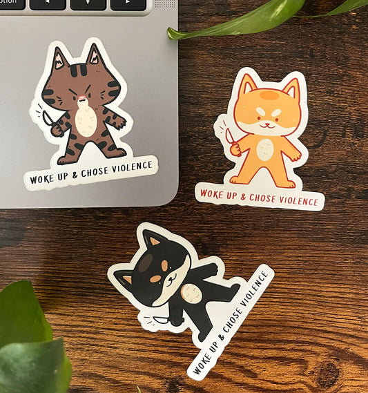 Three stickers of cats and dogs holding little knives with the caption "Woke up & Chose Violence".