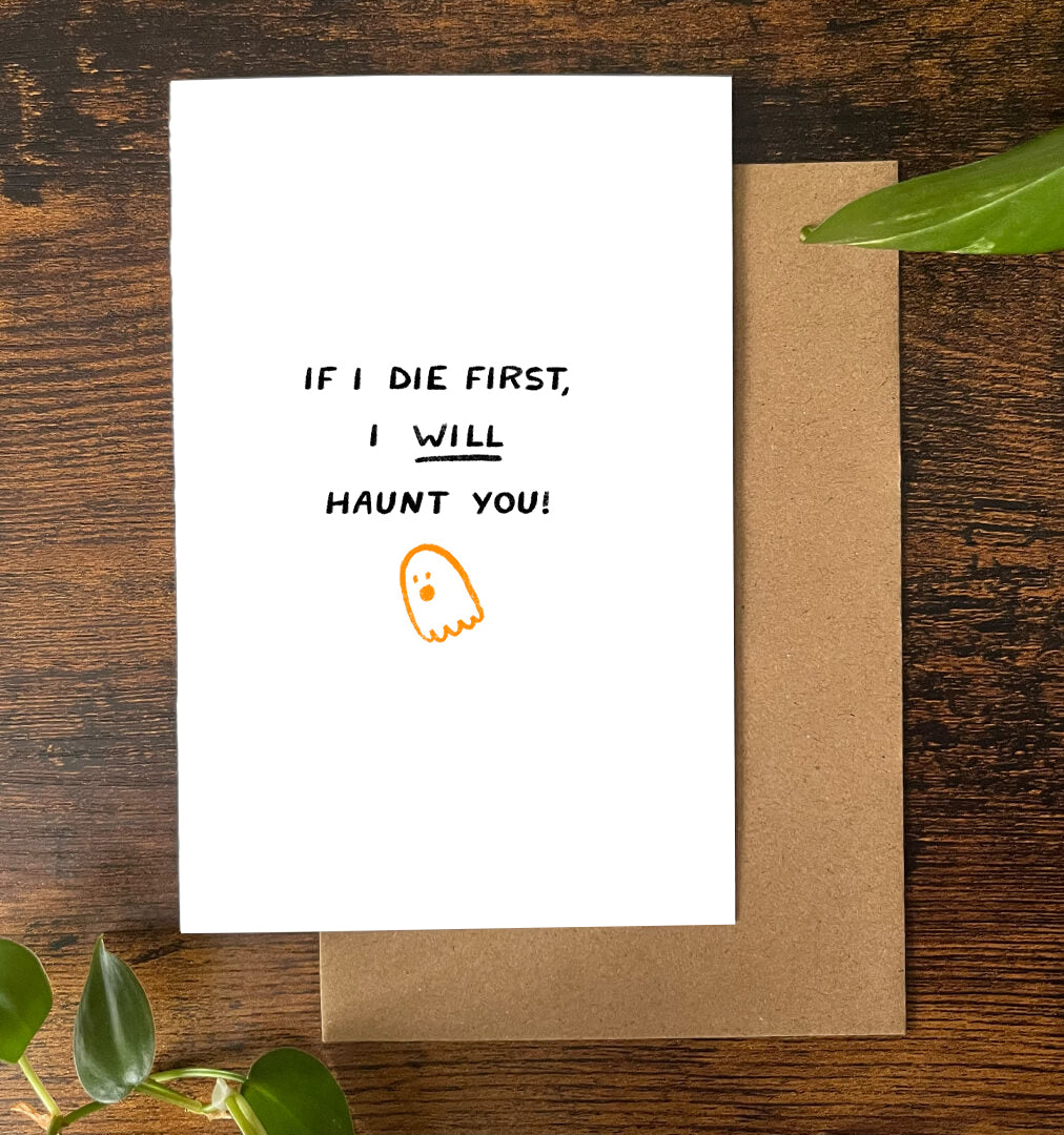 Greeting card with text 'If I die first, I will haunt you!' on a wooden surface.