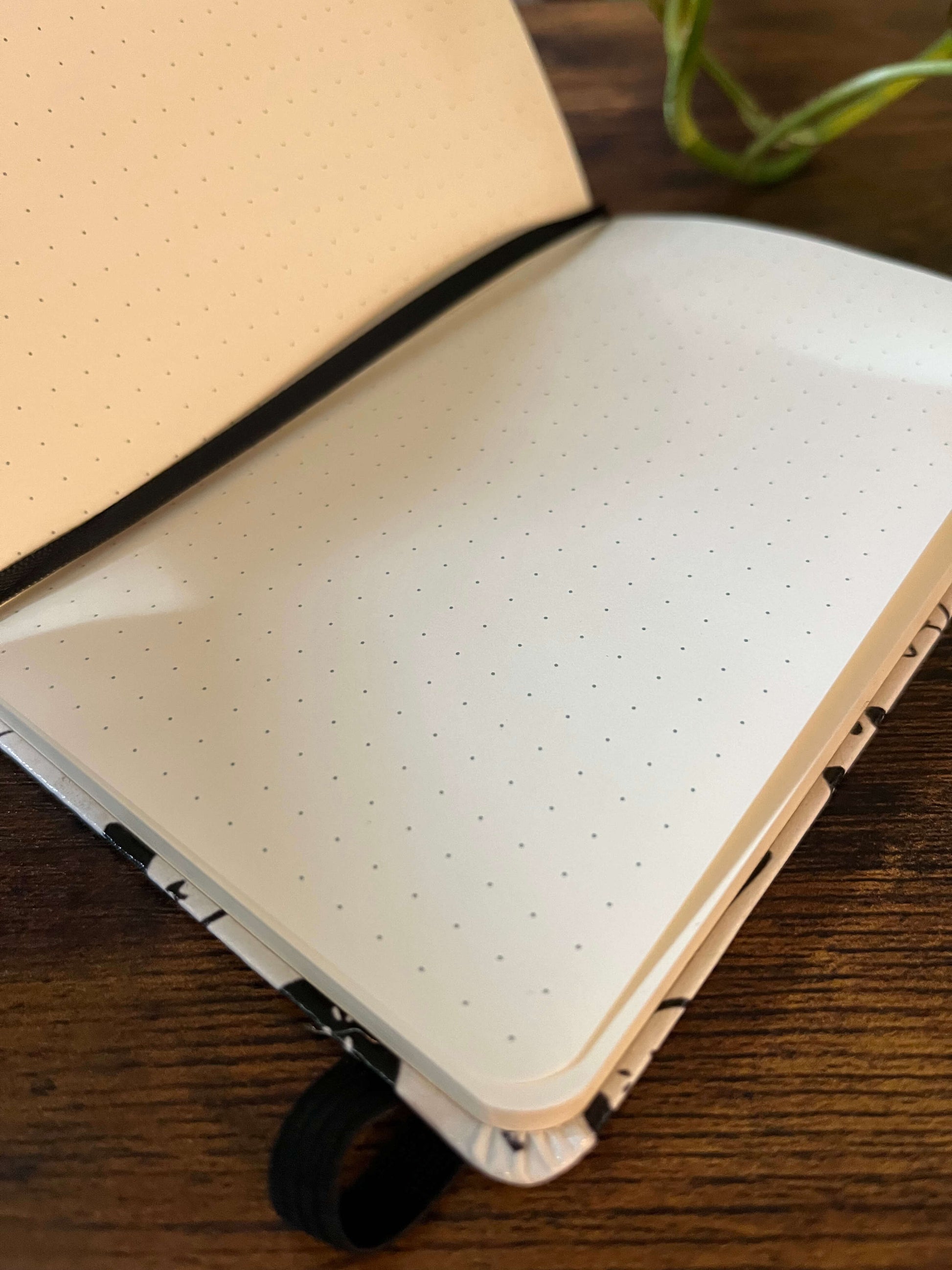 Open notebook with dotted pages, lying on a wooden table. 