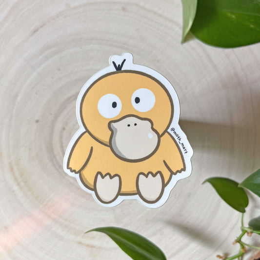 Cartoon yellow duck sticker on a wooden surface with green leaves