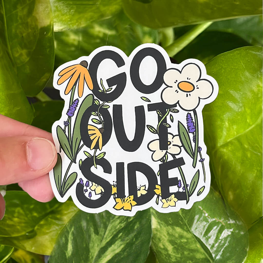 Sticker of "Go Outside" text surrounded by colorful flowers and greenery, including daisies and lavender. 