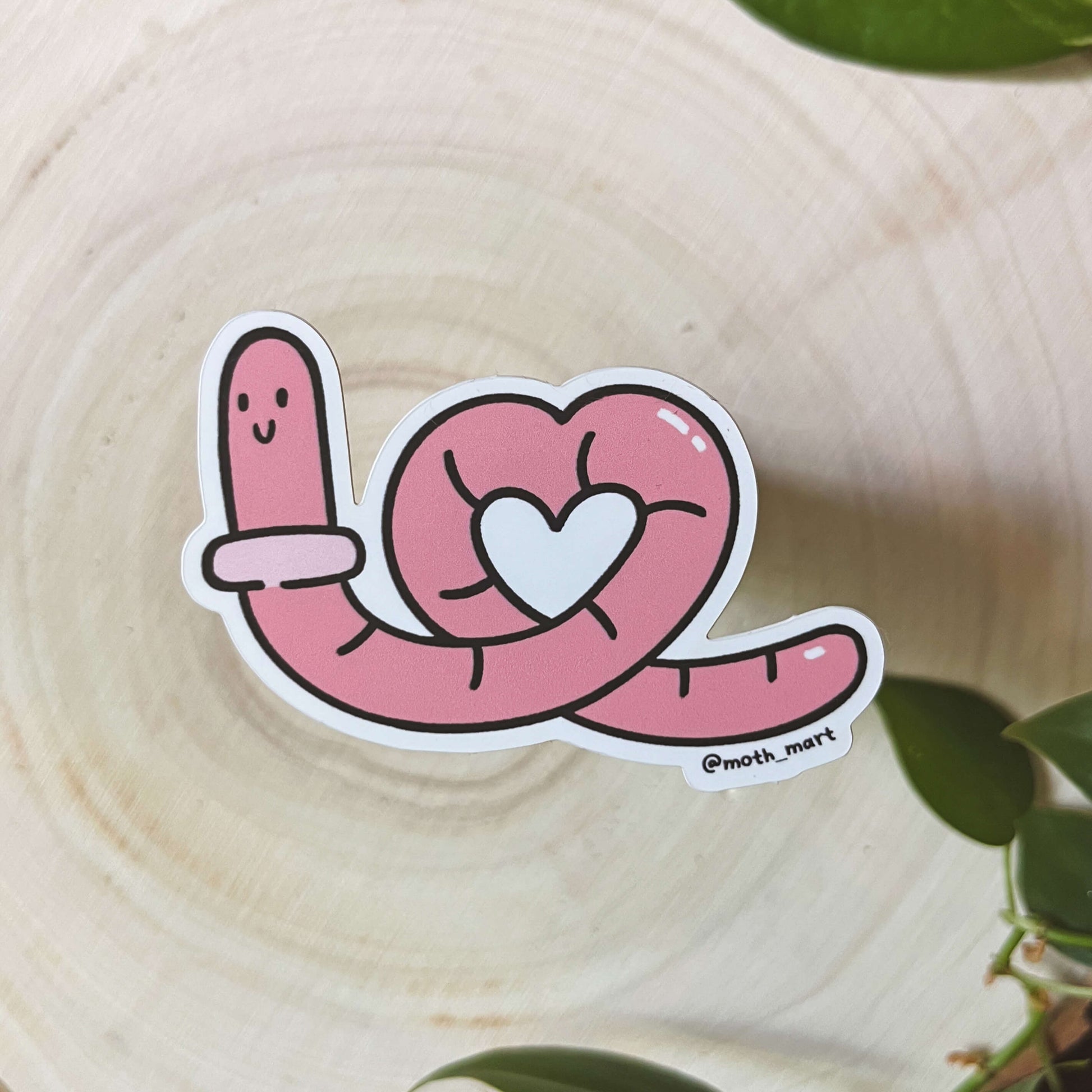 Illustration of pink cartoon worm with a heart on a wooden surface