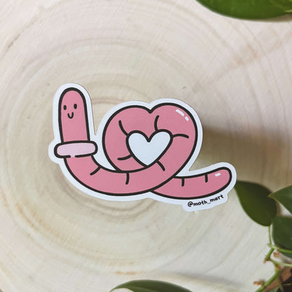Illustration of pink cartoon worm with a heart on a wooden surface