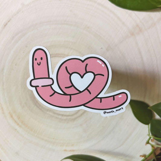 Illustration of pink cartoon worm with a heart on a wooden surface