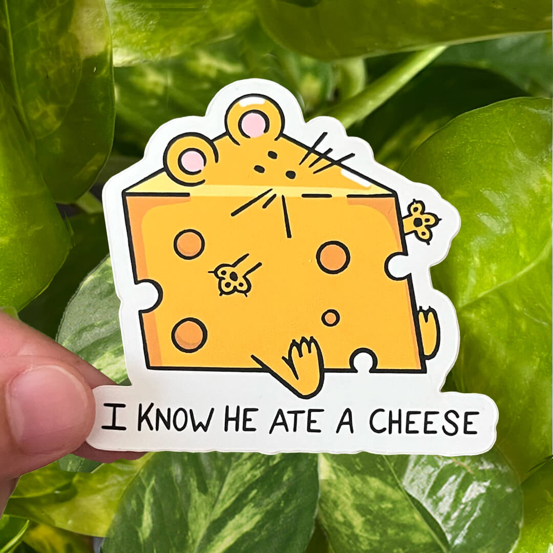 Sticker of a mouse in the shape of a block of yellow cheese with the text "I know he ate a cheese". 