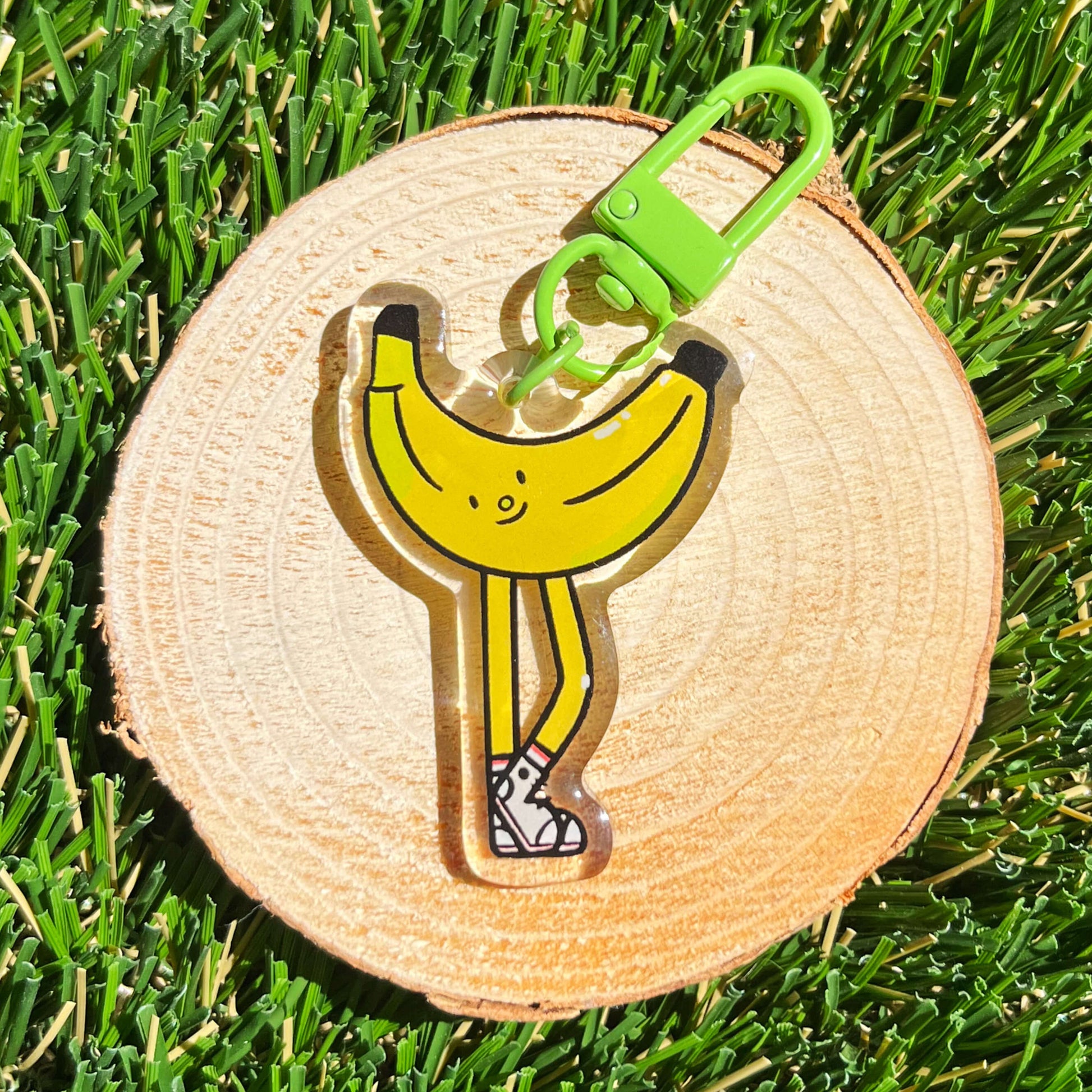 Banana-shaped keychain on a wooden disc with grass background