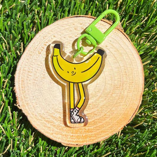 Banana-shaped keychain on a wooden disc with grass background