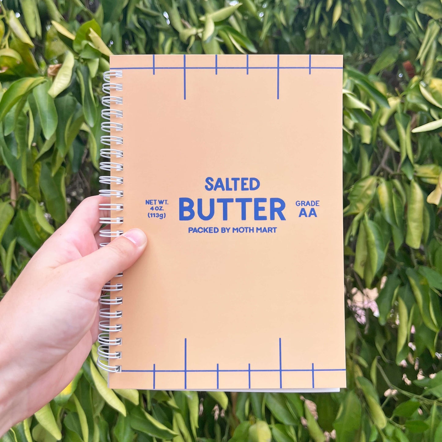 Reusable sticker book titled 'Salted Butter' held against a green leafy background