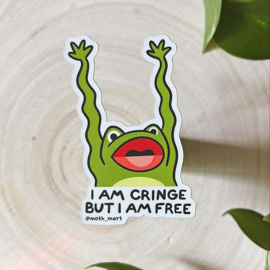 A green frog with its mouth open and long, wiggly arms, with the text "I am cringe but I am free" on a wood background with leaves. 