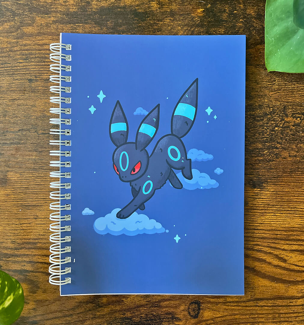 Spiral A5 sticker book featuring a navy blue cat with light blue stripes on clouds surrounded by stars.