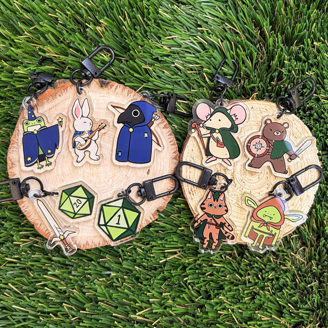 Nine fantasy and gaming-themed animal character acrylic keychains displayed on natural wood slices, displayed on a green grass background.