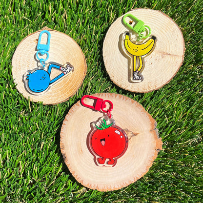 Three colorful fruit keychains on wooden slices with grass background