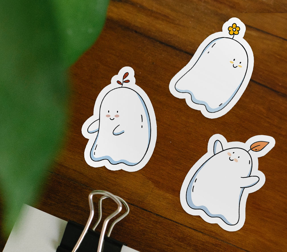 Three cheery ghost stickers, each have plants on their heads. One has an orange leaf, one has a red leaf, and one has a yellow flower.