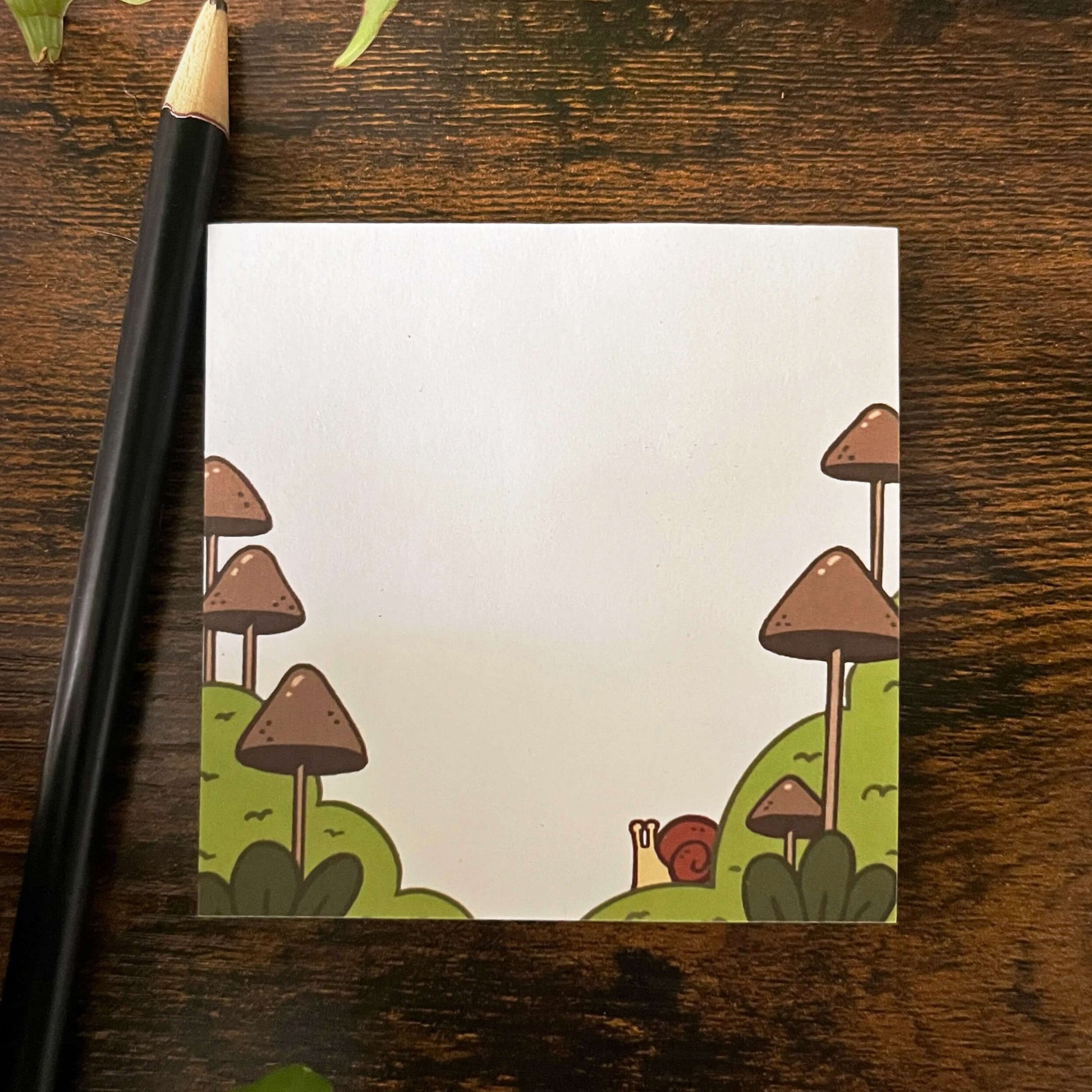 Decorative sticky notes of mushroom with snail. A pencil is nearby.