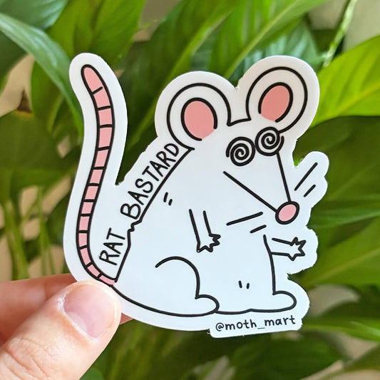 A hand holds a die-cut sticker featuring a cartoon rat. The sticker has black outlines, pink accents, and the text 'RAT BASTARD' and '@moth_mart'.