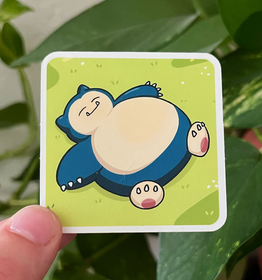 Sticker of blue Pokemon Snorlax laying in the grass.
