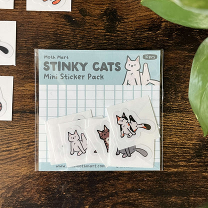 Moth Mart Stinky Cats Mini Sticker Pack with 10 stickers on a wooden surface with stinky cat stickers around.